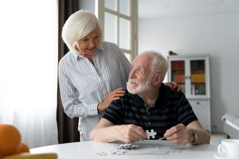 Une femme âgée regarde son mari faire un puzzle