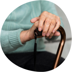 Deux mains d'une personne âgée sont posées sur une canne