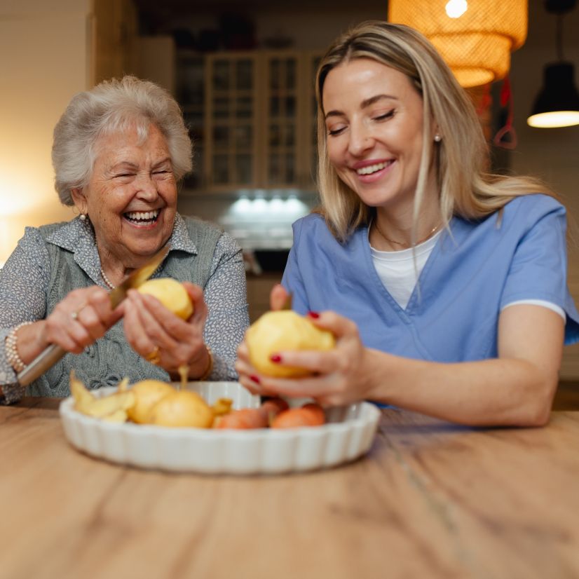 Personne âgée préparant un repas avec une aide à domicile
