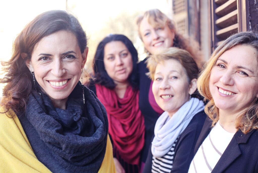 Cinq femmes souriantes ensemble.